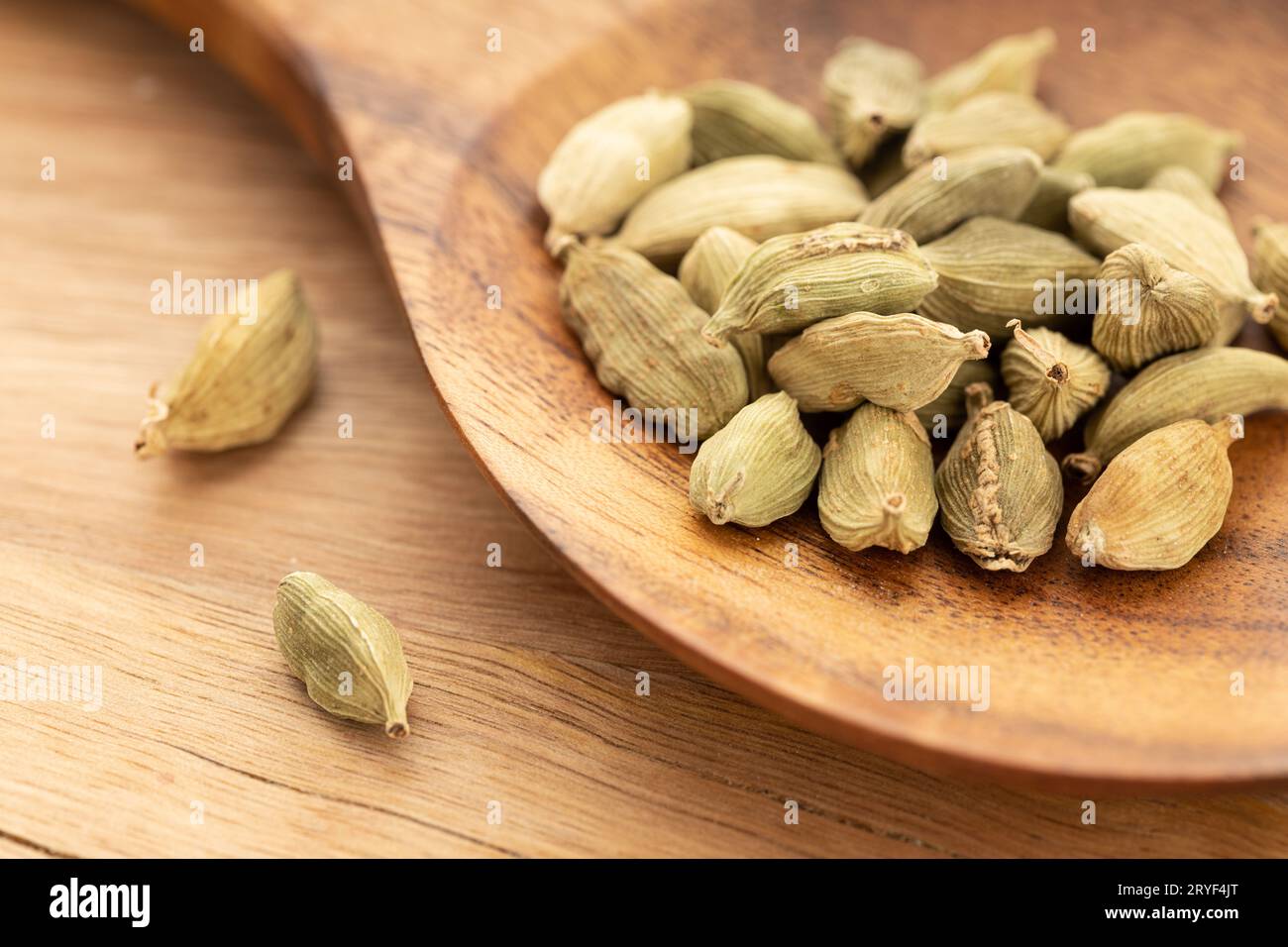 Cardamomo su cucchiaio di legno. Cottura delle spezie. Elettaria cardamomum Foto Stock