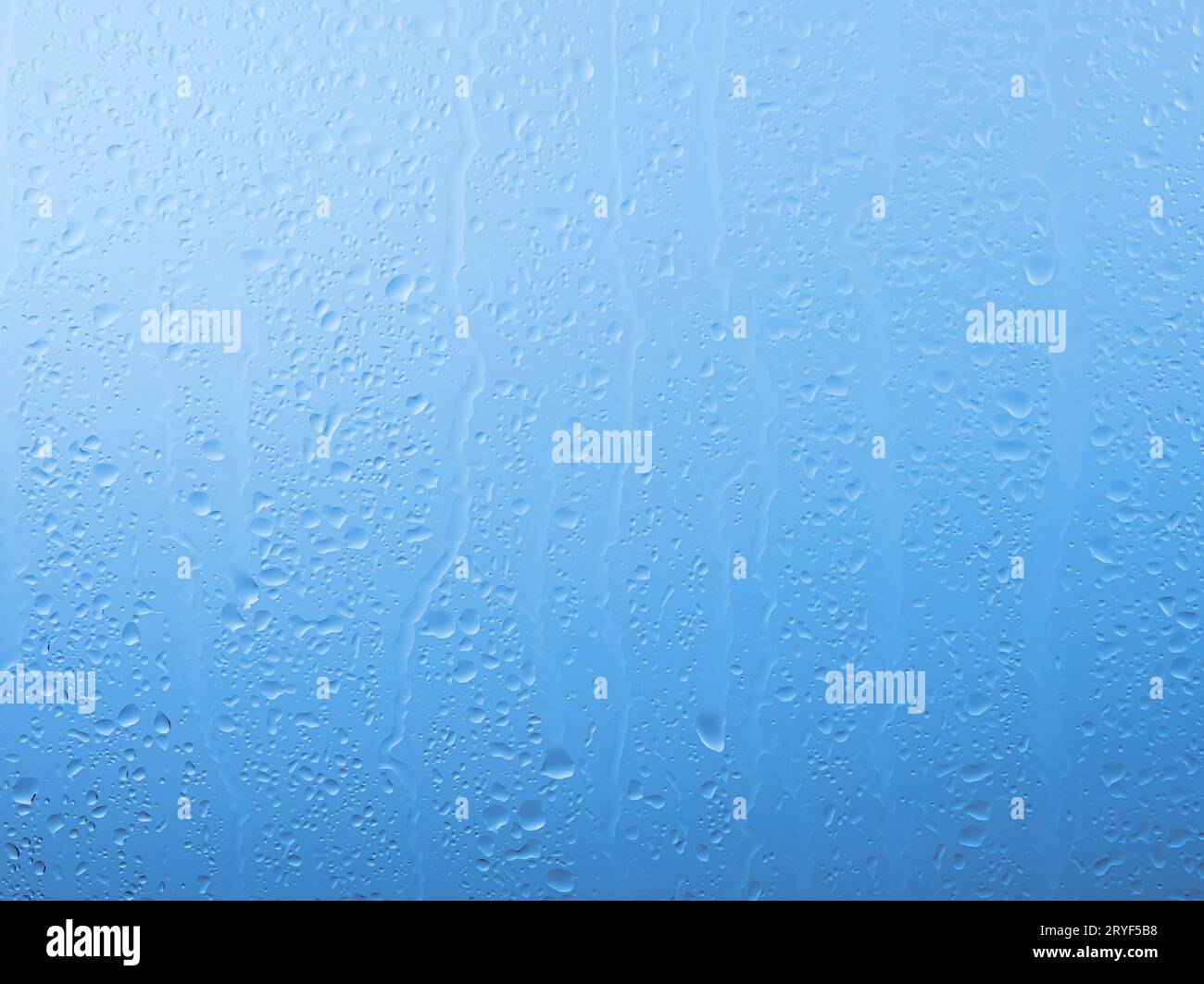 Gocce di pioggia sulla finestra di vetro sopra il cielo grigio e blu Foto Stock
