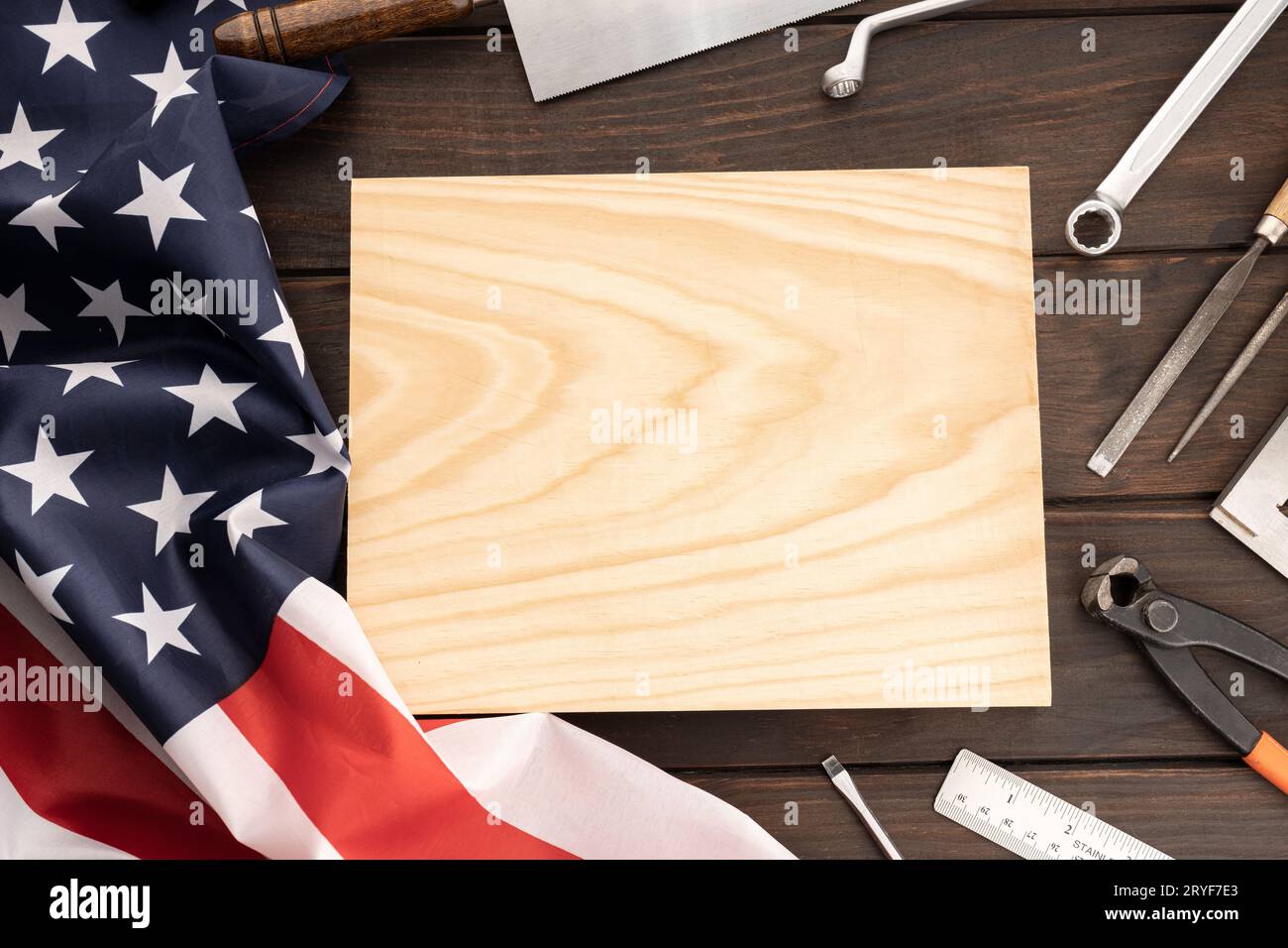 Vista dall'alto della bandiera americana , degli attrezzi da lavoro e della tavola di legno vuota per il testo. Mock-up modello. Background concettuale del giorno del lavoro Foto Stock