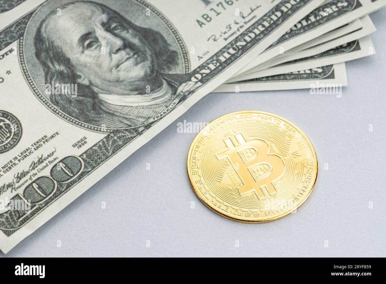 Moneta di Bitcoin e un mucchio di banconote in dollari USA. Blockchain money vs. fiat money Concept Foto Stock