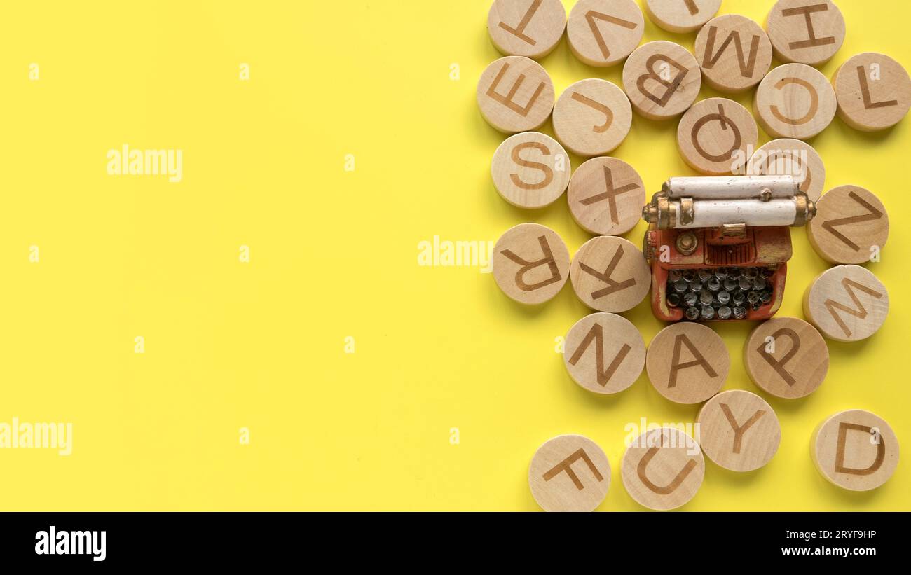 Concetto di apprendimento dell'inglese, ricerca di parole e informazioni. Lettera alfabetica inglese e macchina da scrivere in miniatura su sfondo giallo con spazio di copia Foto Stock