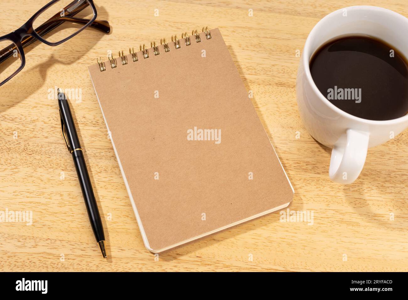 Blocco appunti in cartone vuoto su scrivania in legno con tazza di caffè e occhiali. Modello mock up Foto Stock