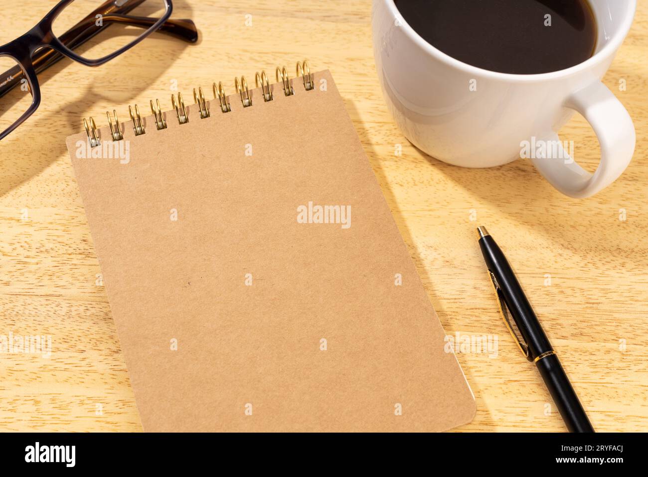 Blocco appunti in cartone vuoto su scrivania in legno con tazza di caffè e occhiali. Modello mock up Foto Stock