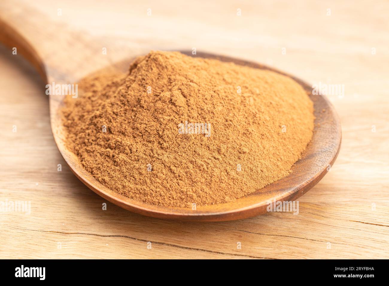 Polvere di cannella in cucchiaio di legno su tavola di legno. Primo piano Foto Stock