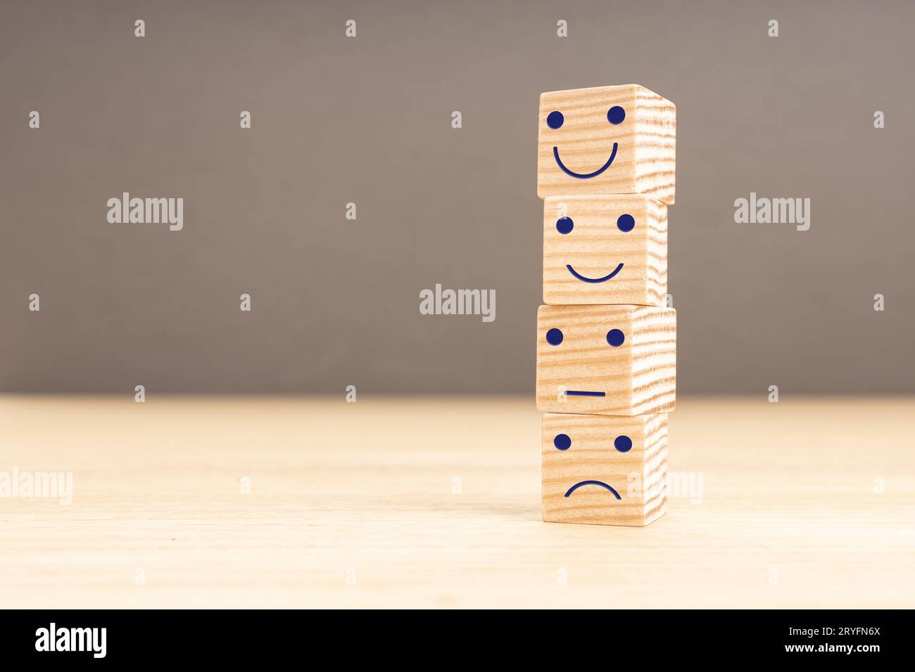 Valutazione del servizio clienti e sondaggio sulla soddisfazione. Emoticon viso su blocchi di legno impilati. Copia spazio Foto Stock