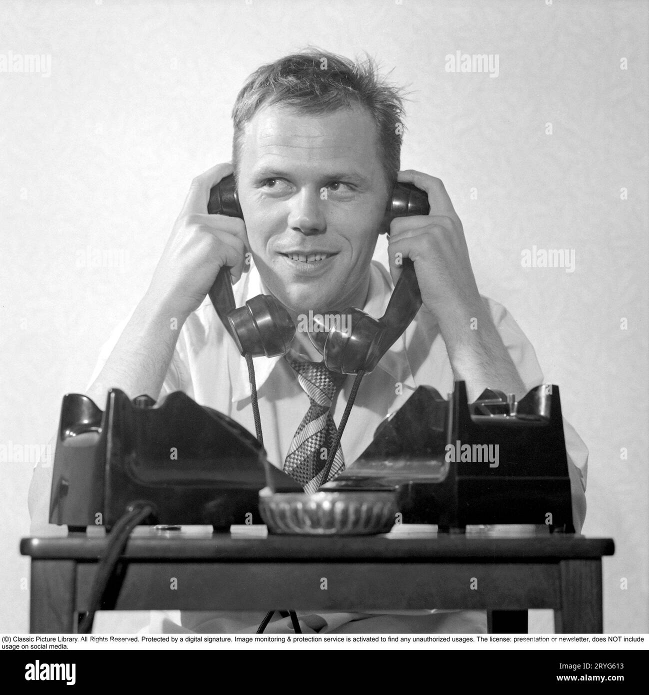 Negli anni '1950 Sixten Larsson con due telefoni che sembrano occupati e sembra che stia parlando in due ricevitori contemporaneamente, uno contro ogni orecchio. Svezia 1952. Rif. Conard 2020 Foto Stock