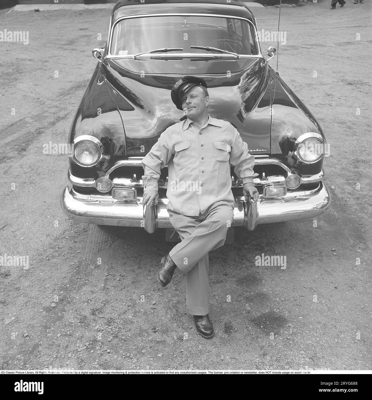 Negli anni '1950 Un uomo vicino alla sua auto ed è visibilmente orgoglioso e forse un po' arrogante. Forse non così strano come è il proprietario di un'impressionante auto americana del marchio Chrysler Imperial. Negli anni '1950, molti dettagli sono stati cromati: griglia, paraurti, modanature. Svezia 1951. Kristoffersson rif. BP31-6 Foto Stock