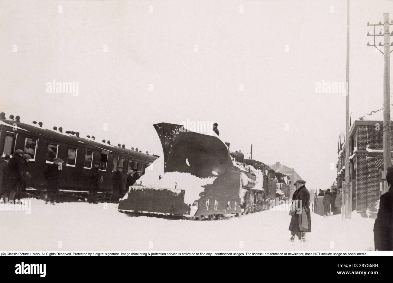 Tempesta di neve negli anni '1920 Una tempesta di neve ha colpito la Svezia meridionale e la regione della Scania, e qui si trova il treno innevato della costa occidentale alla stazione di Svalöv nel febbraio 1929. Tuttavia, la prontezza delle ferrovie statali è alta e davanti alla locomotiva a vapore è montato un vomere da neve di un modello più grande, che allontana la neve dai binari di fronte al treno. Sulle piattaforme, la gente cammina nella neve alta. Foto Stock