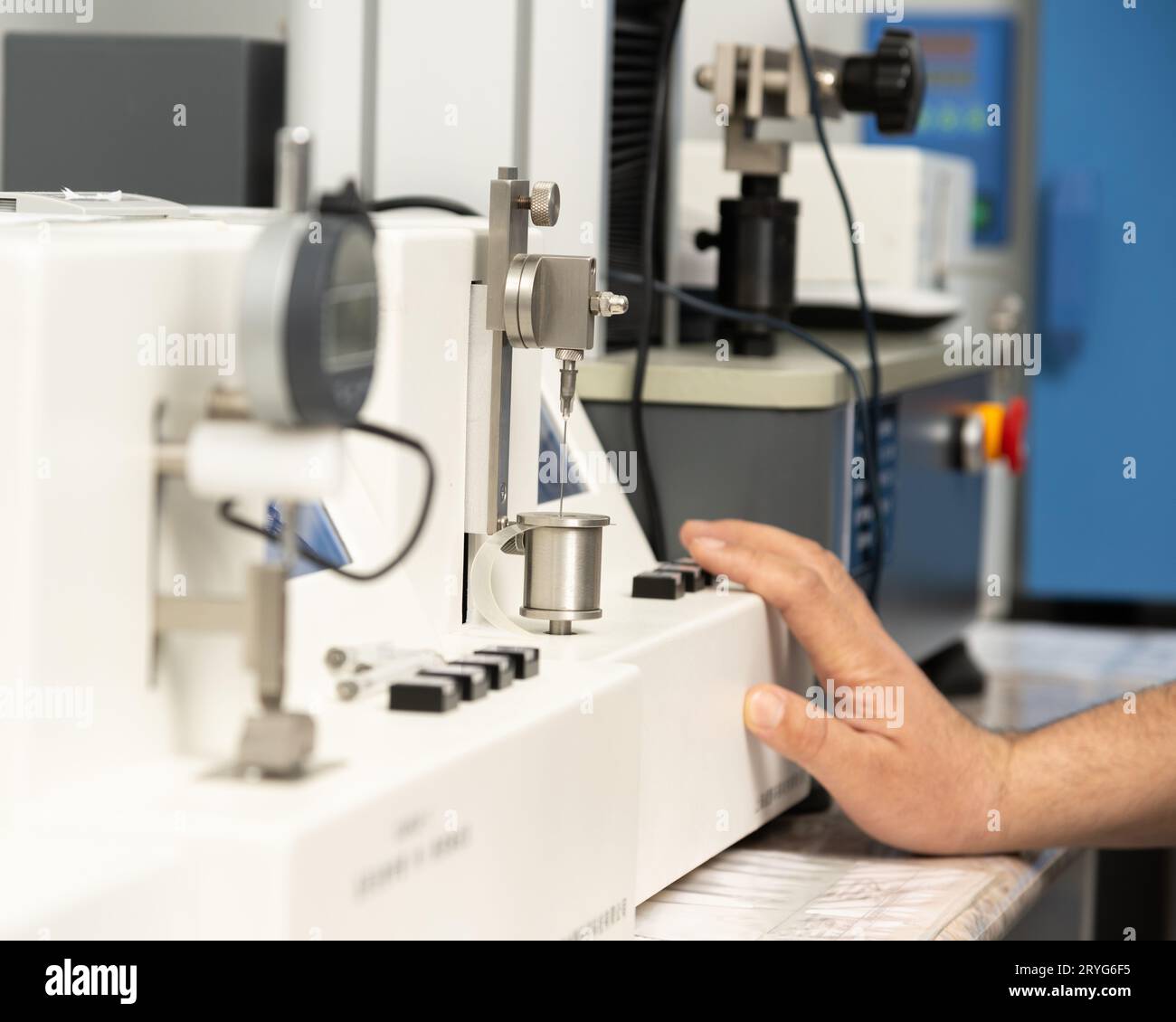 Un primo piano di una mano che utilizza una macchina medica per testare e produrre siringhe farmaceutiche Foto Stock