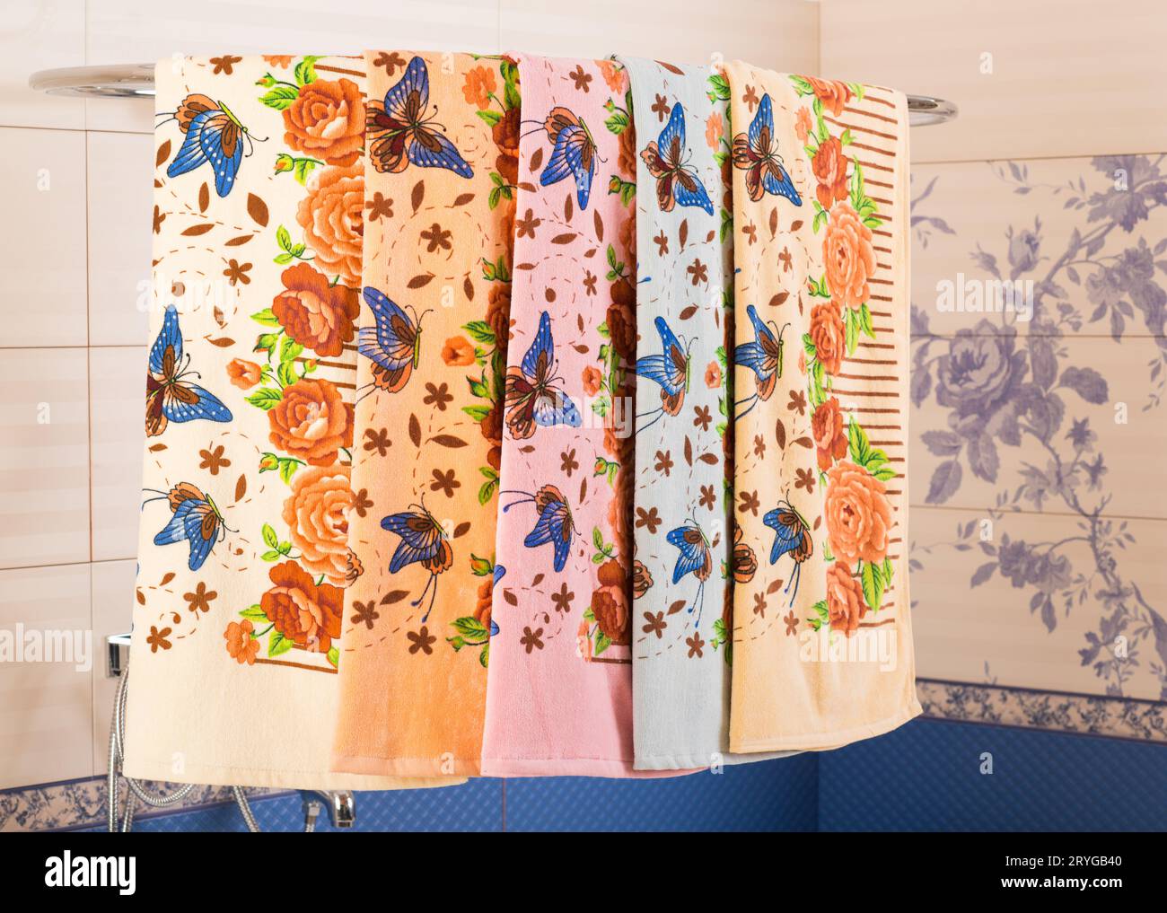 Una fila di asciugamani colorati a motivi geometrici appesi su un supporto doccia sopra una vasca da bagno Foto Stock