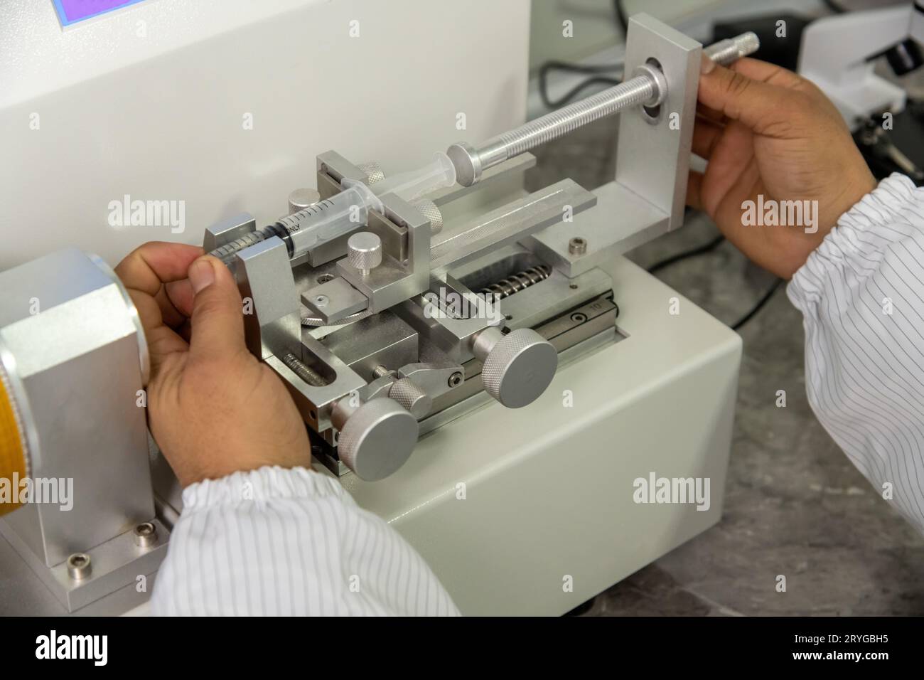 Un primo piano delle mani che lavorano su una macchina in un magazzino di produzione medica per siringhe Foto Stock