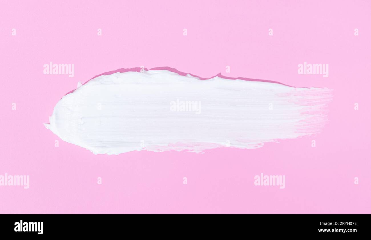 Striscio di crema bianca per viso o corpo isolato su sfondo rosa Foto Stock