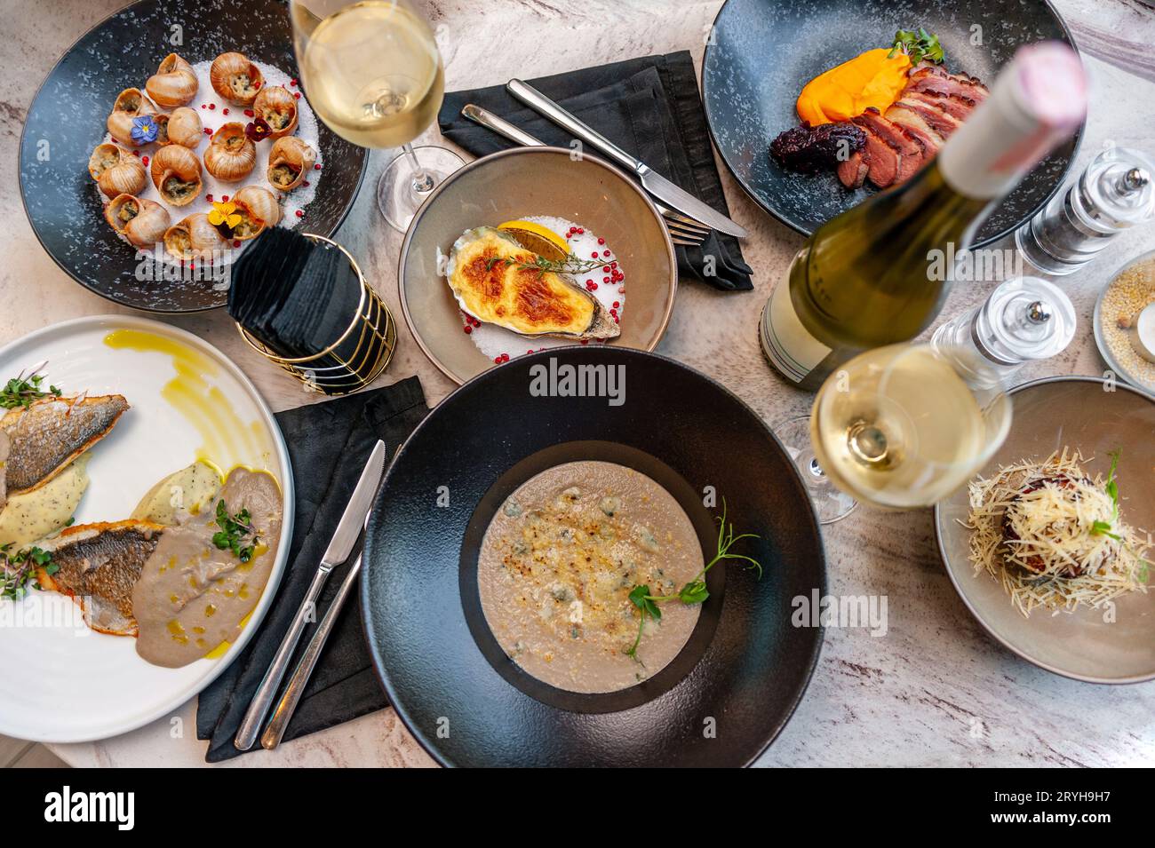 Menu mediterraneo con piatti di pesce. Lumache d'uva, filetto di spigola, ostriche al forno, zuppa di funghi. Foto di alta qualità Foto Stock