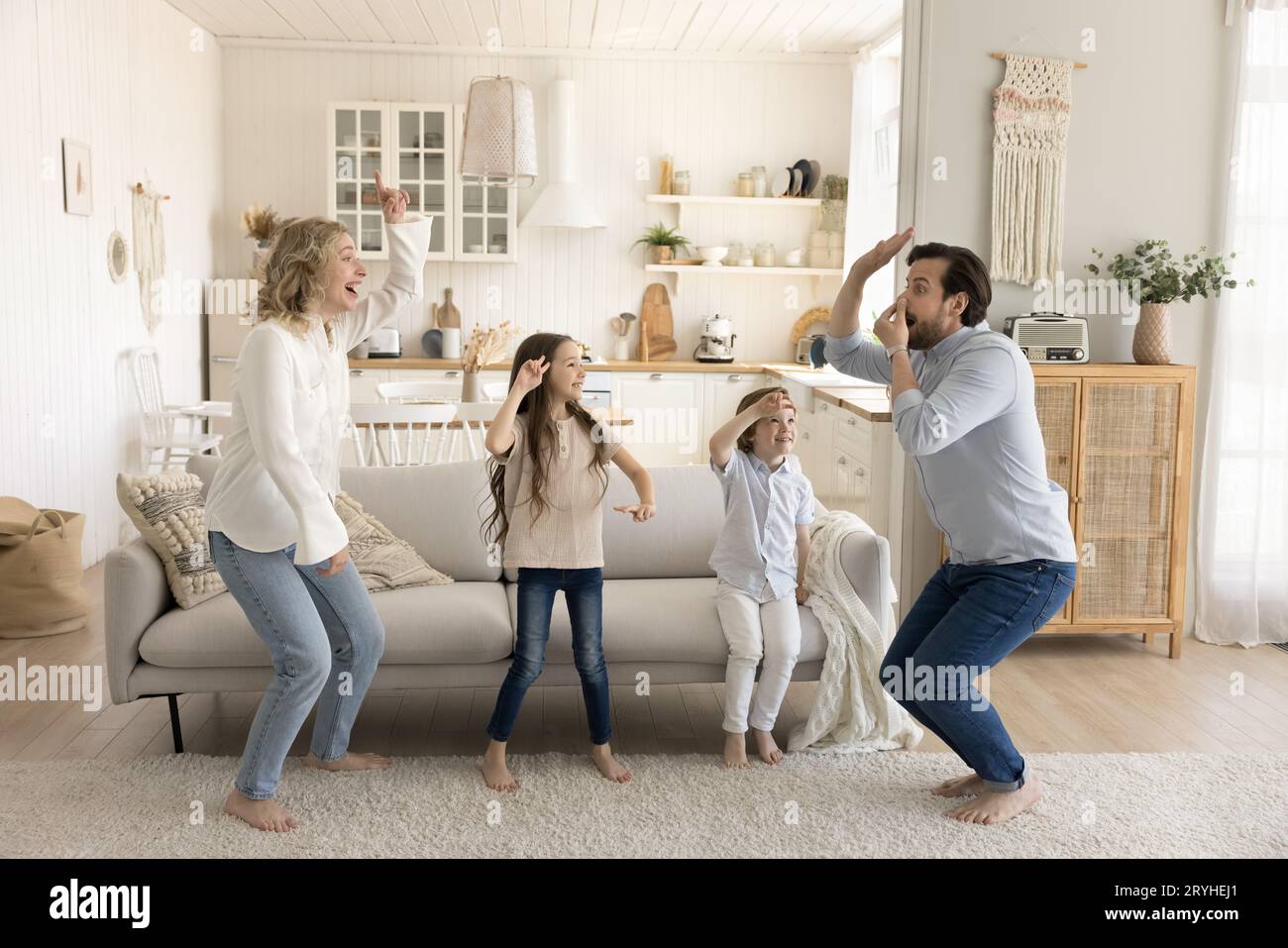 Genitori eccitati ballano con i bambini a casa Foto Stock