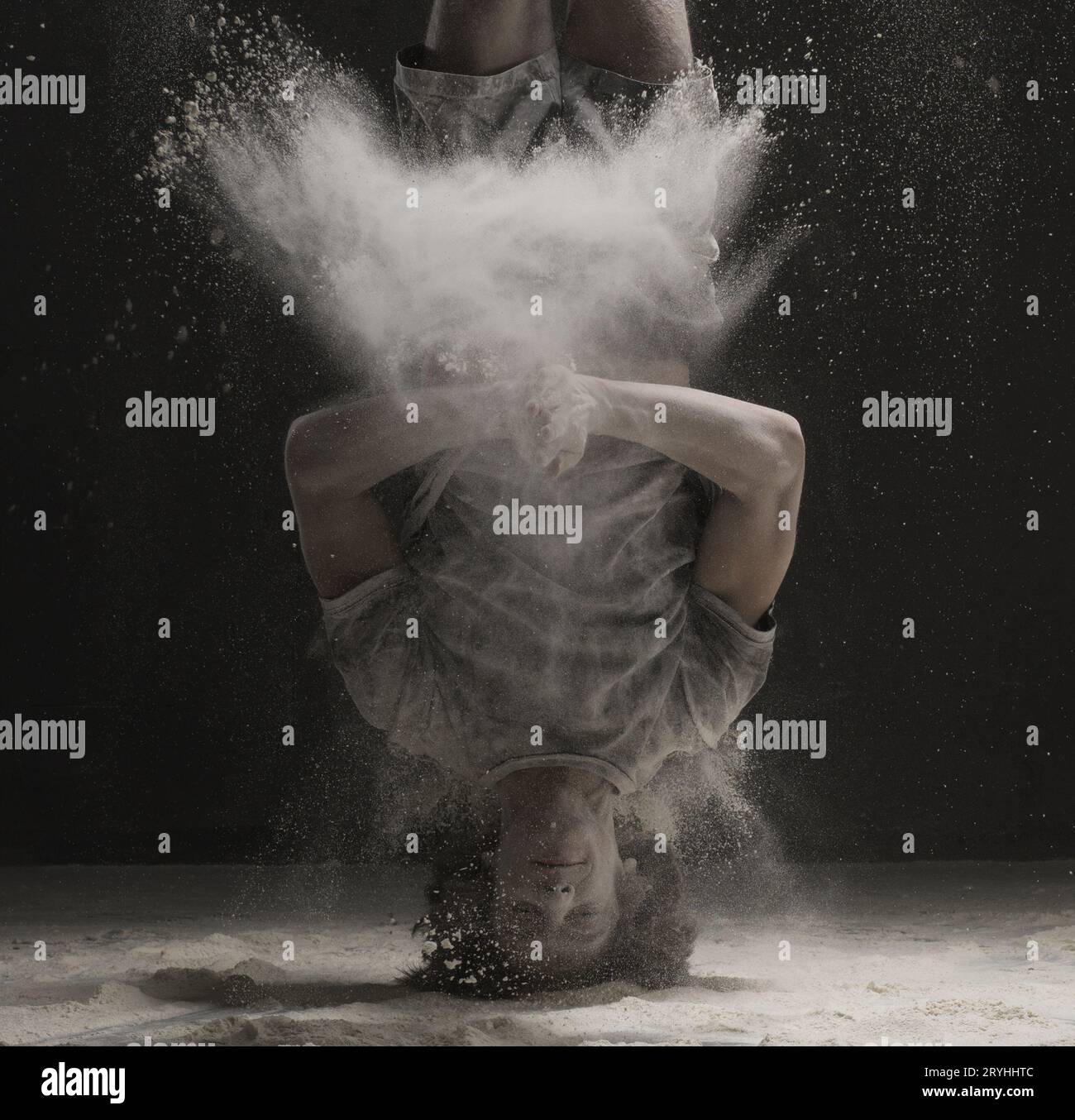 Giovane ballerino facendo un headstand in una nube di polvere di view Foto Stock