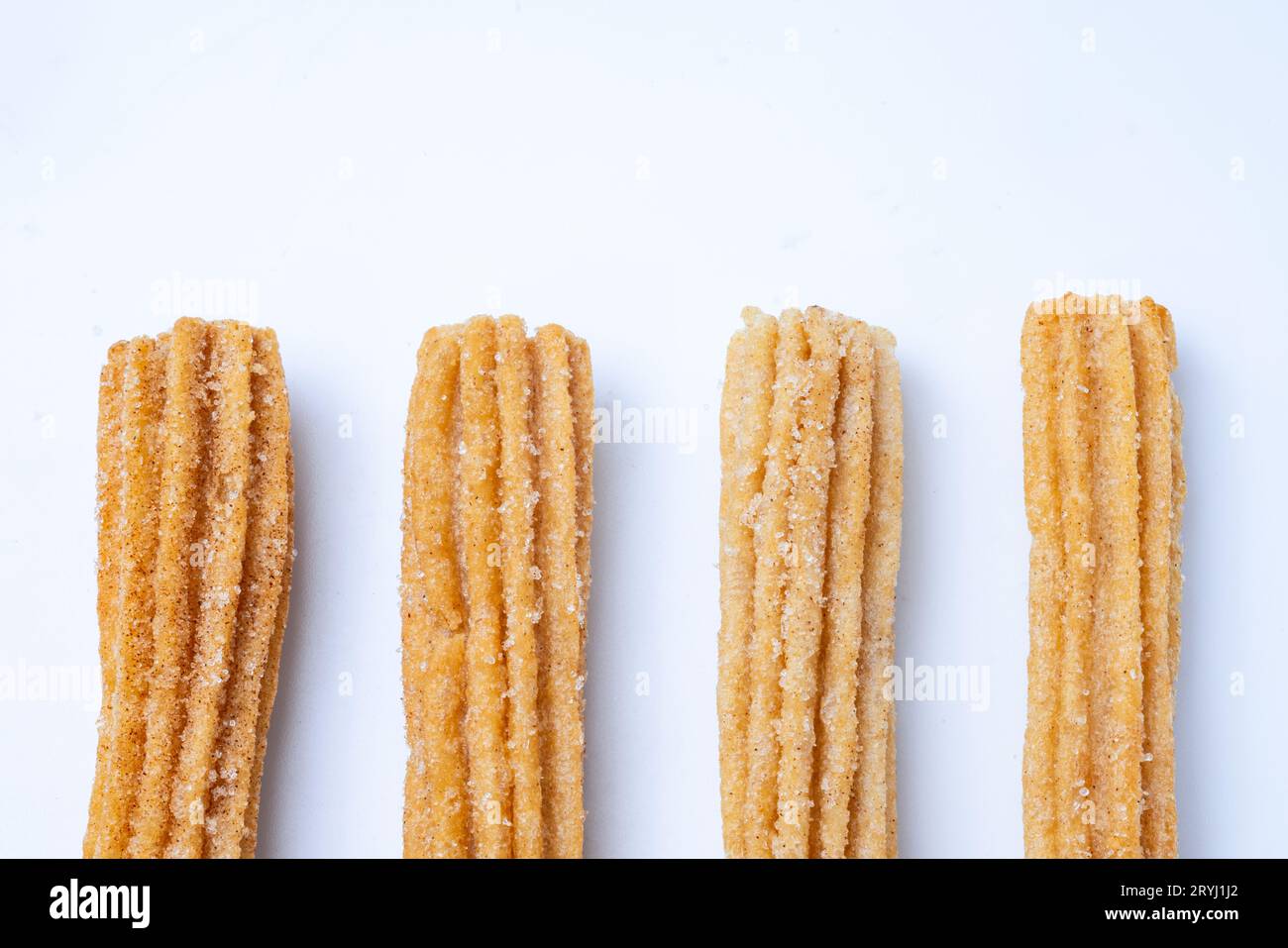 I churros si allineano su un tavolo bianco. Foto Stock