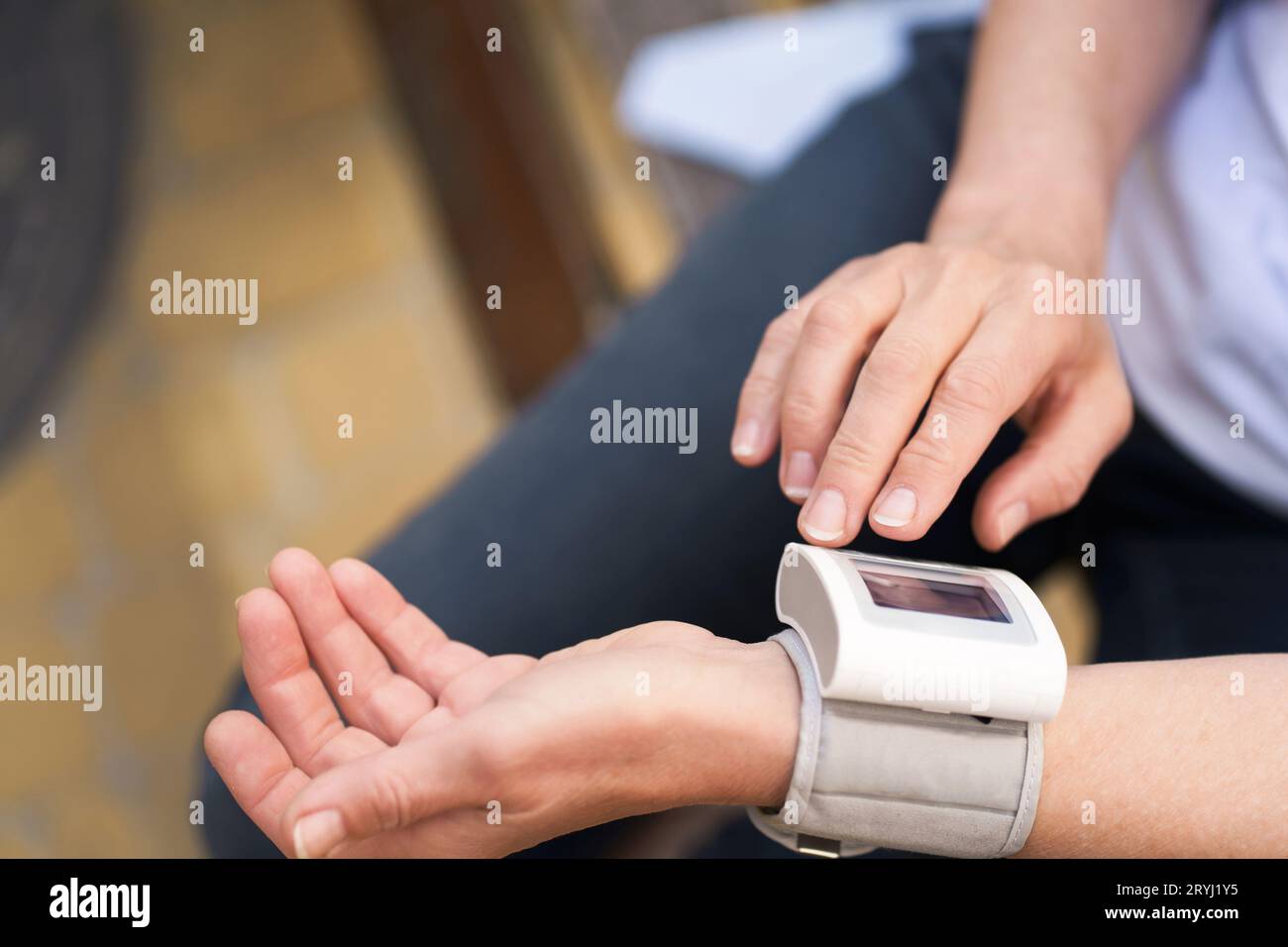 Primo piano delle mani di una donna anziana che tiene il dispositivo di misurazione della pressione all'aperto. L'immagine rappresenta il concetto di monitor dello stato Foto Stock