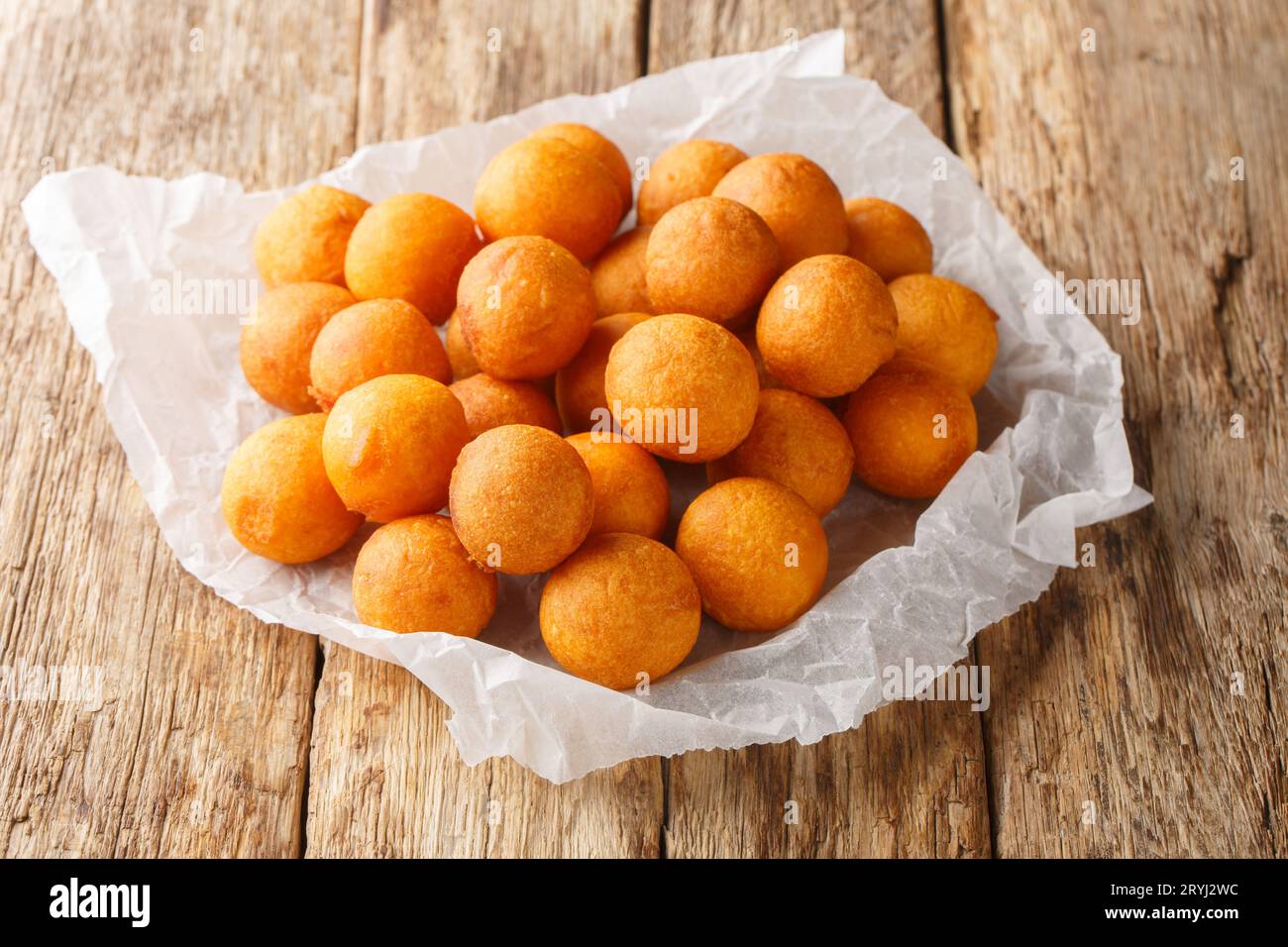 palle di patate dolci fritte a forma di uovo di quaglia fritte in profondità con l'olio in primo piano sul tavolo di legno. Orizzontale Foto Stock