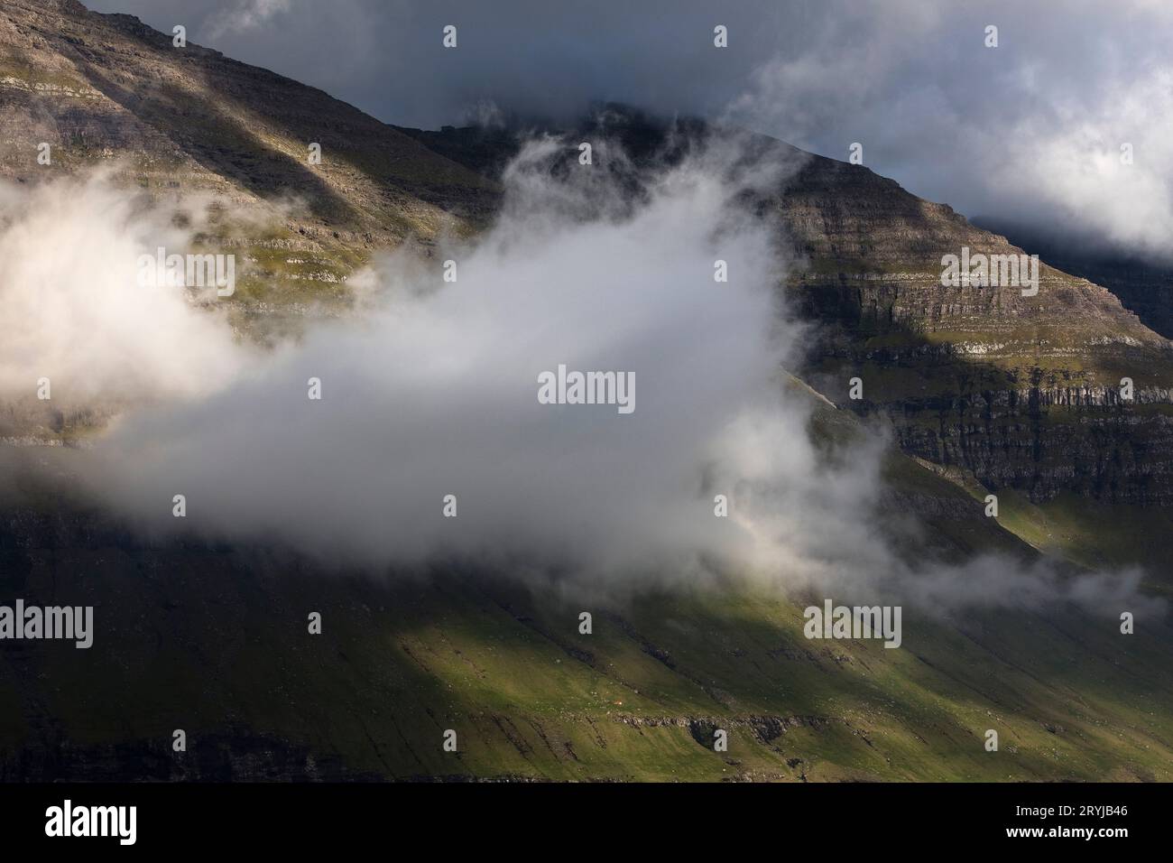 Nuvola con un'illuminazione spettacolare sulla costa occidentale dell'isola nord atlantica di Kunoy, Isole Faeroe Foto Stock