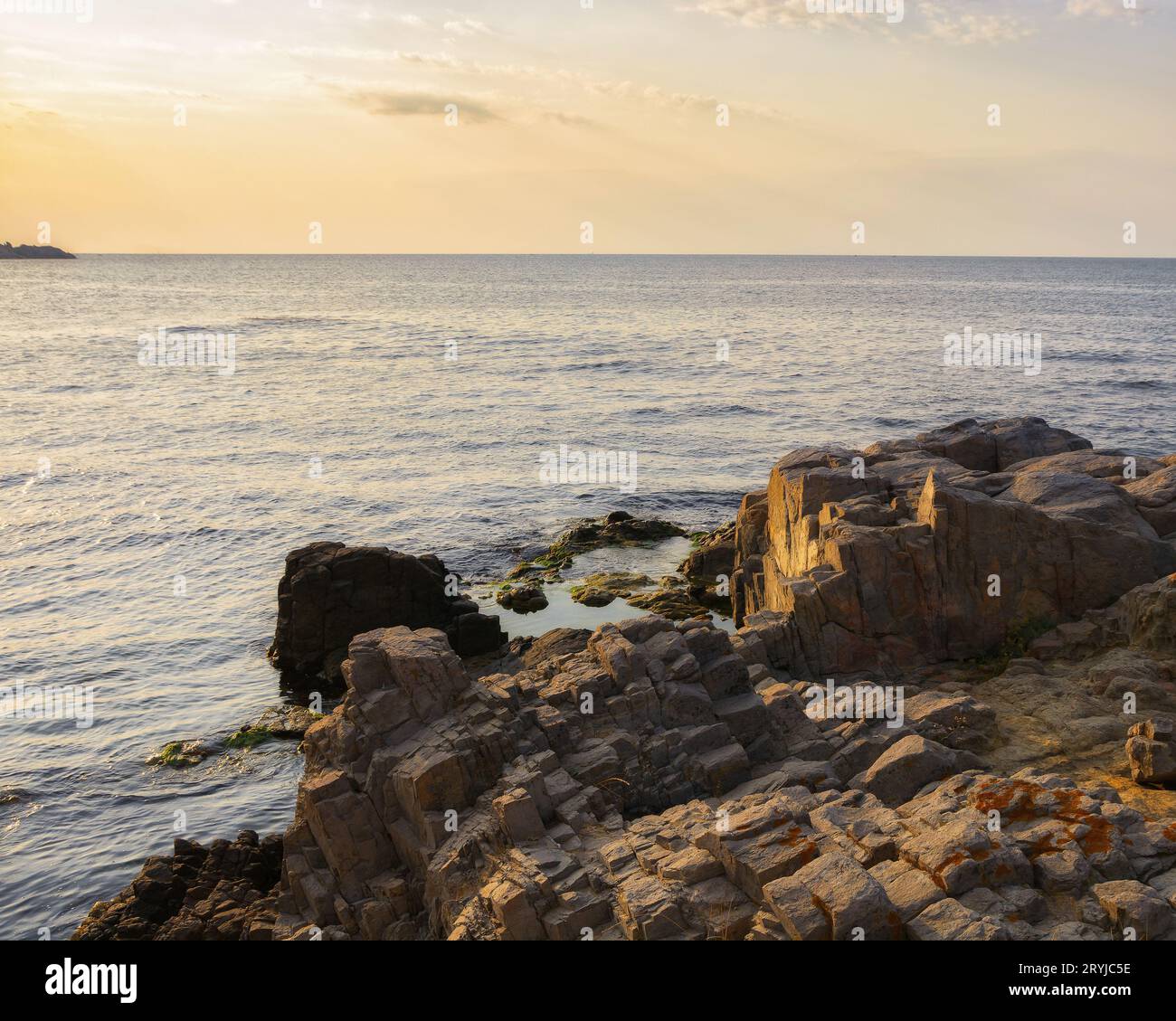 costa del mare con pietre e massi alla luce del mattino. clima calmo con cielo senza nuvole sopra l'orizzonte. sfondo delle vacanze estive Foto Stock