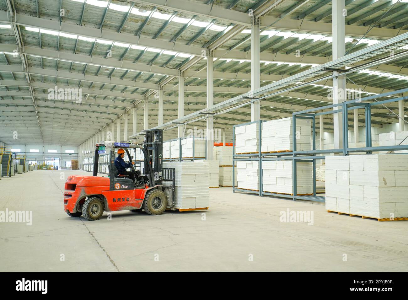 Contea di Luannan, Cina - 27 luglio 2023: I lavoratori guidano carrelli elevatori per trasportare pannelli di lana in ceramica in una fabbrica. Foto Stock