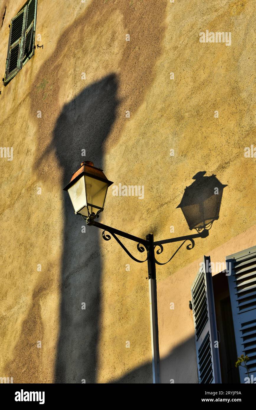 Palo lampada all'esterno di un edificio con parete dipinta di giallo malinconico nella cittadella genovese di Bastia, Corsica, Francia Foto Stock