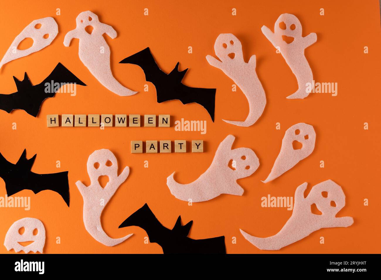 Fantasmi bianchi e mazza per la festa di Halloween. Immagine fantasma della carta di avvolgimento su sfondo arancione vista dall'alto. Fumetto Creepy Whisper. Fai-da-te fatto a mano. Impostare i caratteri boo. Parola frase di legno della lettera. Foto Stock