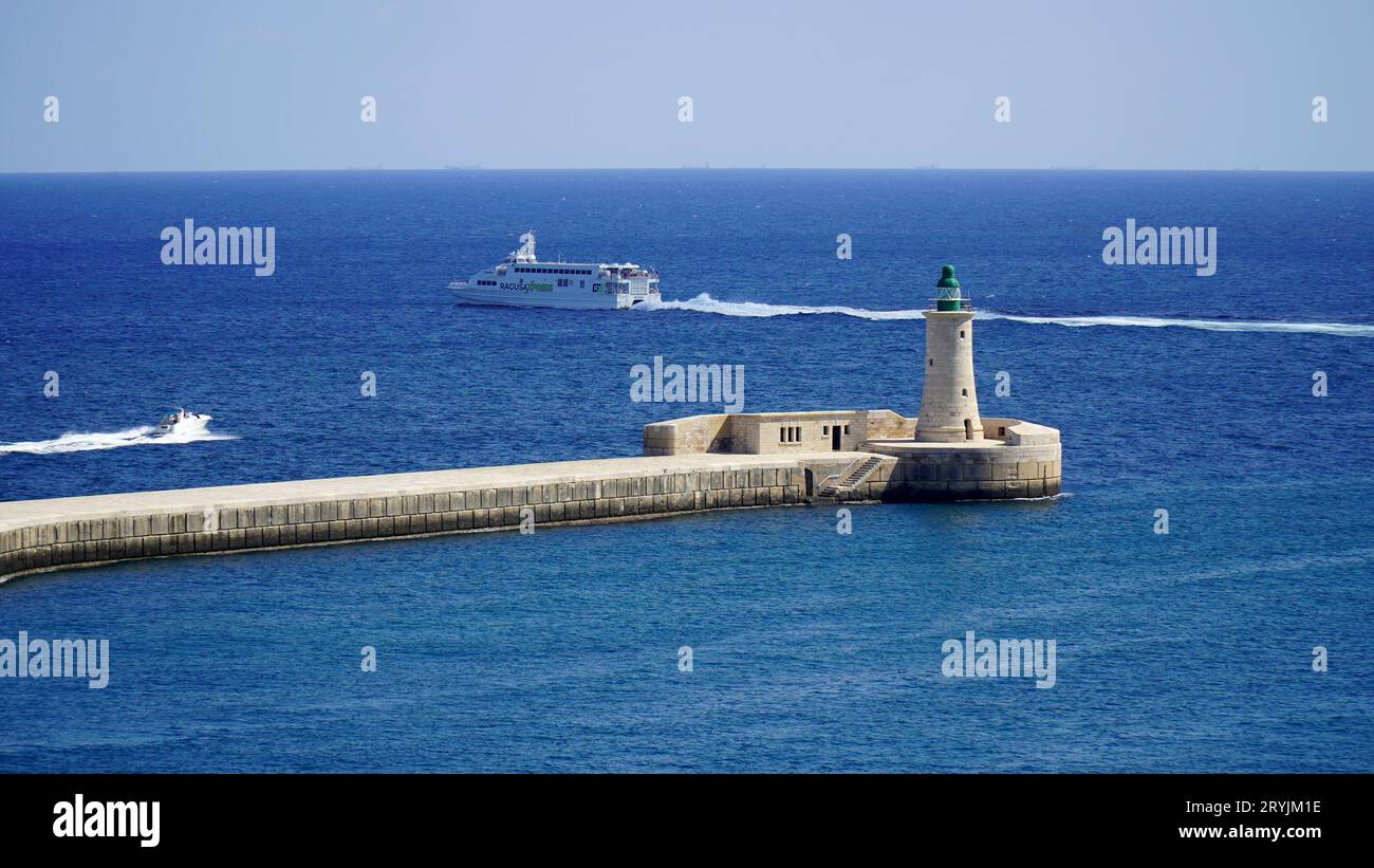 St Faro di Elmo Breakwater, Grand Harbour, Valletta, Malta. Torre in muratura con lanterna verde costruita nel 1908. Traghetto per la Sicilia, Italia. Foto Stock