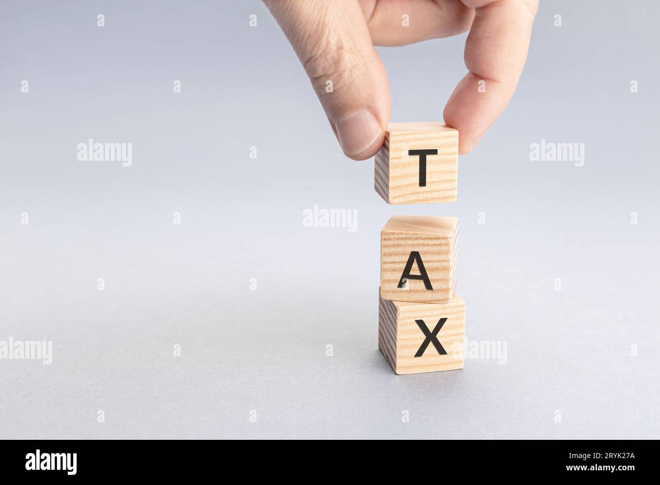 Concetto di tassazione. Mano che mette un blocco con la parola DI IMPOSTA in cima ad altri. Spazio di copia Foto Stock