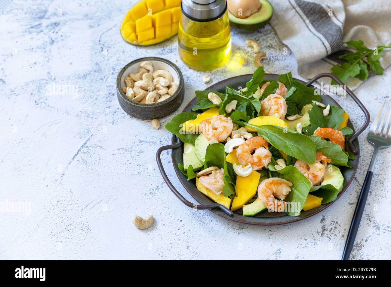 Insalata sana con rucola, spinaci, mango, avocado, gamberi, condimento in noci pecan e vinaigrette su un tavolo in pietra grigia. Poliziotto Foto Stock