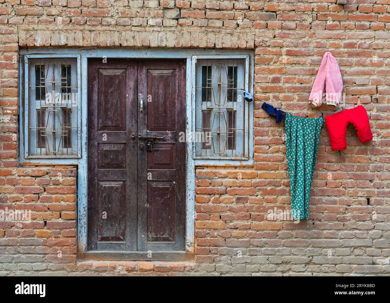 Closthi lavanderia colorata asciutto fuori di una casa. Casa tradizionale in mattoni nepalese Foto Stock
