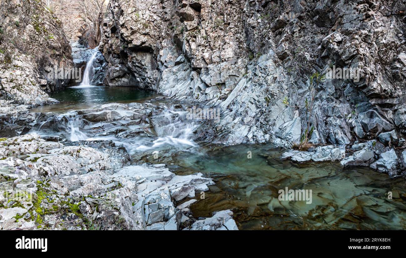 Cascata che spruzza su un lago e scorre attraverso il fiume con formazione geologica rocciosa. Foto Stock