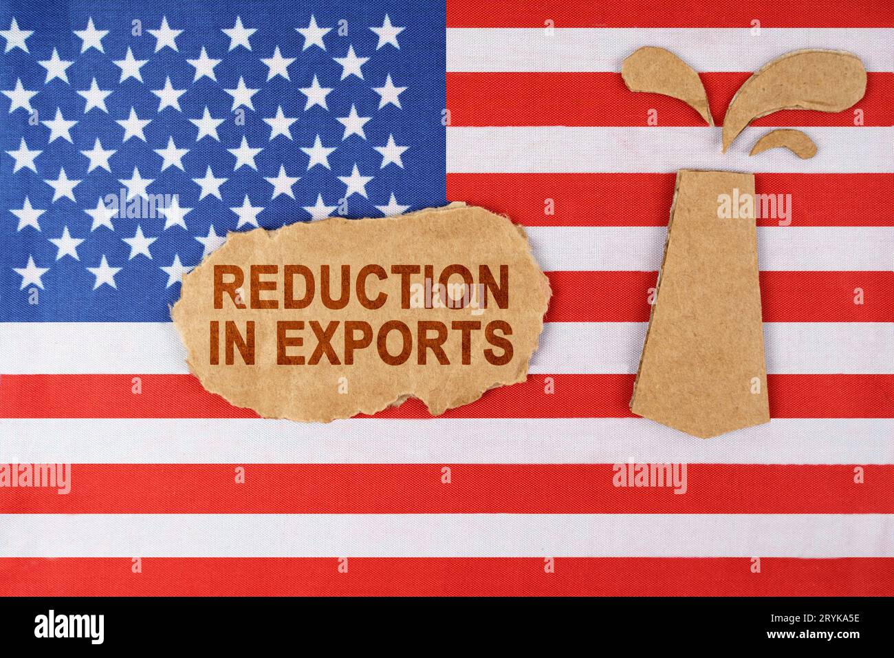 Sulla bandiera degli Stati Uniti c'è una piattaforma petrolifera tagliata fuori dal cartone e un cartello con l'iscrizione "riduzione delle esportazioni". Foto Stock