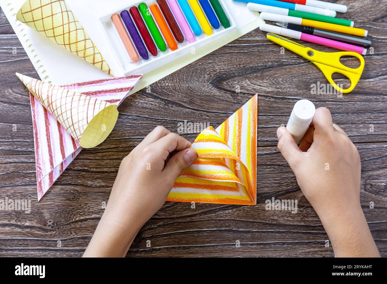 Fase delle istruzioni 7. Gelato di carta su un tavolo di legno. Progetto estivo d'arte per bambini, fatto a mano, artigianato per bambini. Foto Stock