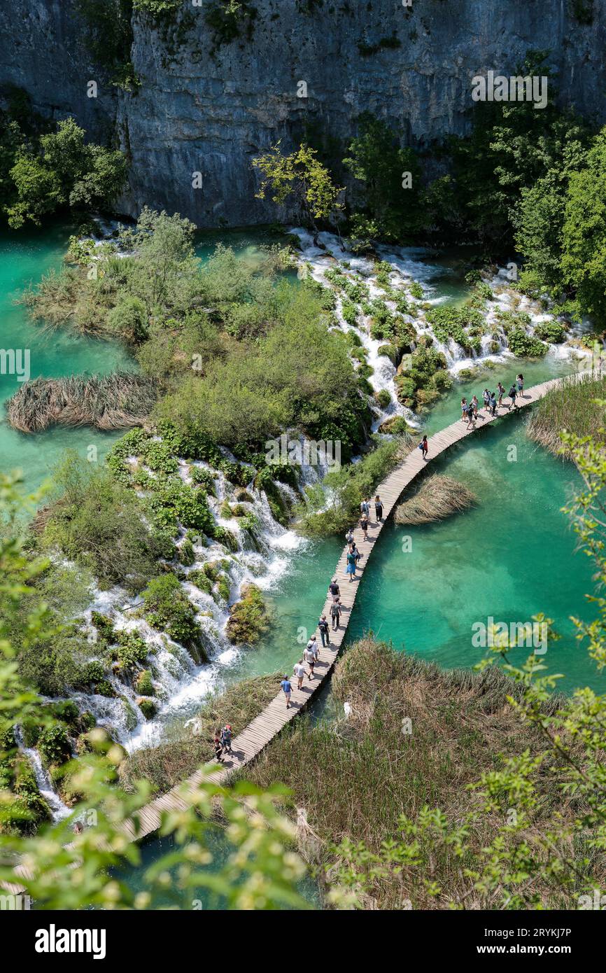 La gente cammina su un sentiero in legno attraverso acque turchesi nel parco nazionale di Plitvice, Croazia Foto Stock