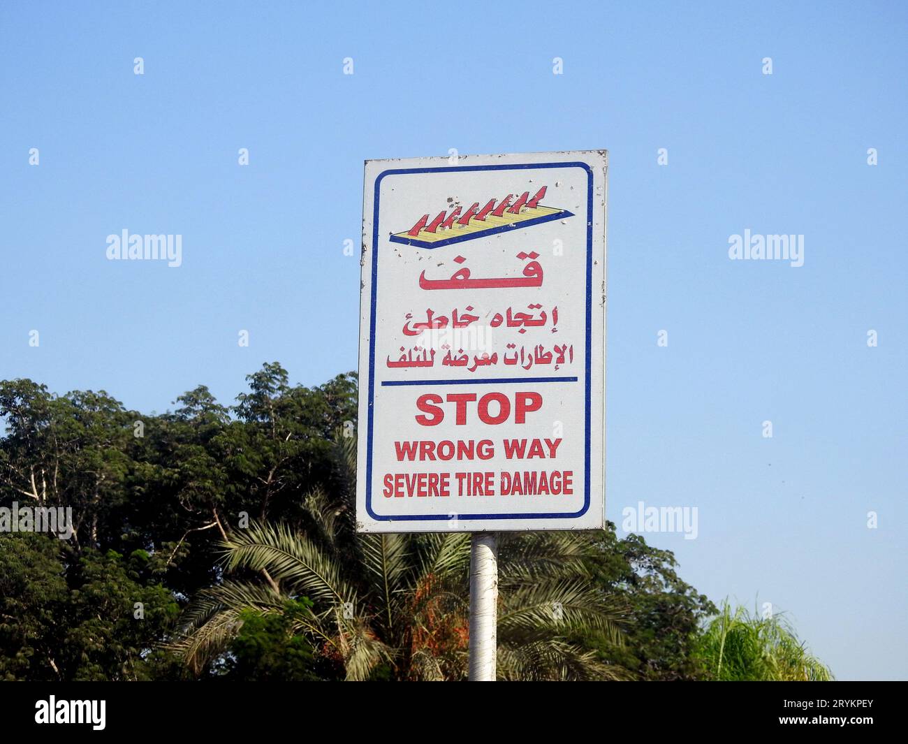 Un cartello segnaletico stradale in arabo e inglese, traduzione di parole arabe ( Stop, Wrong Way, severe Tire Damage ) come precauzione prima che si verifichi una barriera Foto Stock