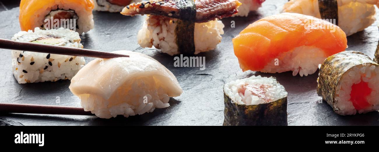 Sushi con bacchette panoramiche. Nigiri di pesce bianco e salmone Foto Stock