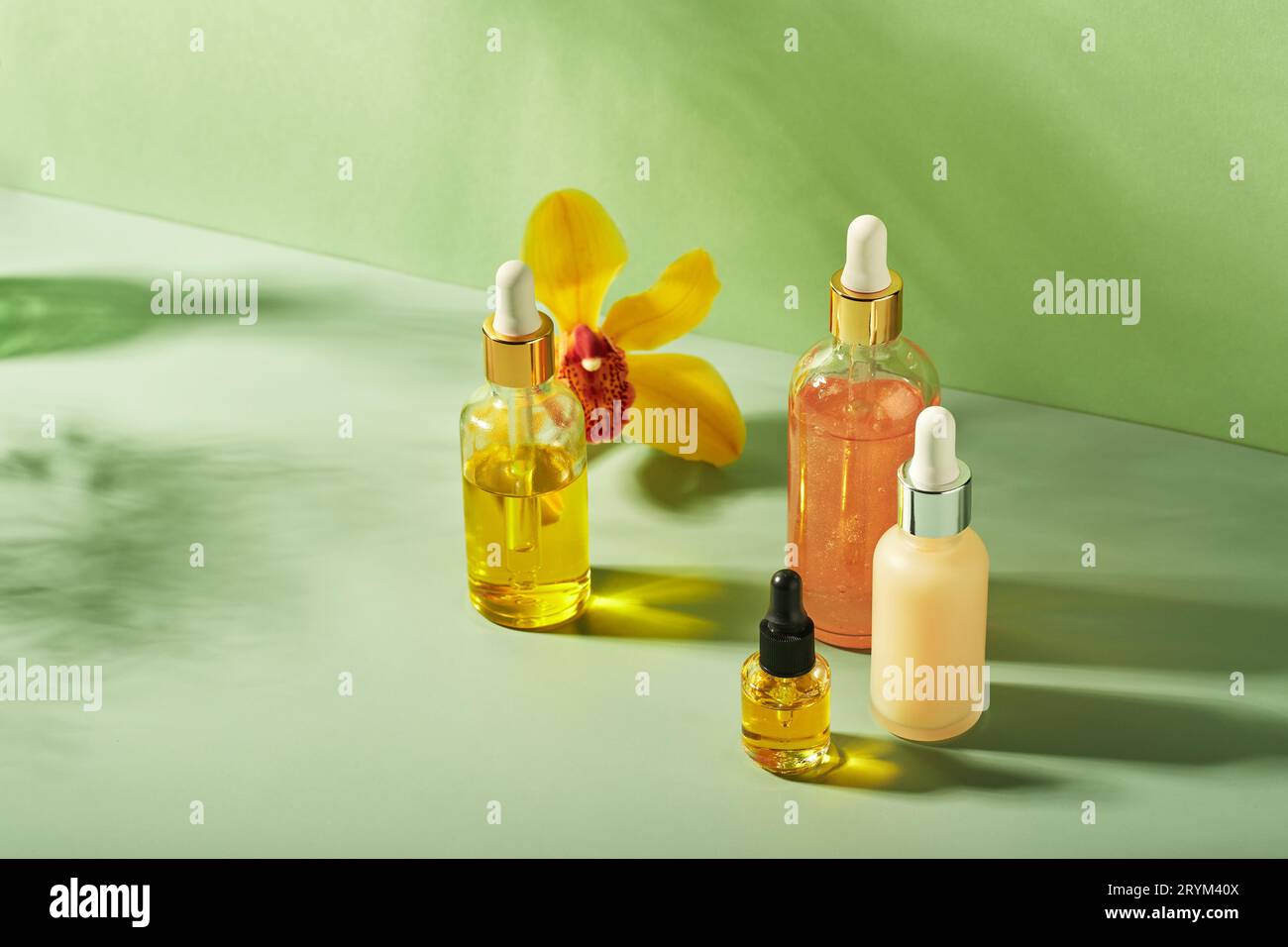 Prodotti cosmetici in bottiglie di vetro con fiori di orchidea - sieri, crema, gel, oli. Concetto per la cura del viso e del corpo, benessere Foto Stock