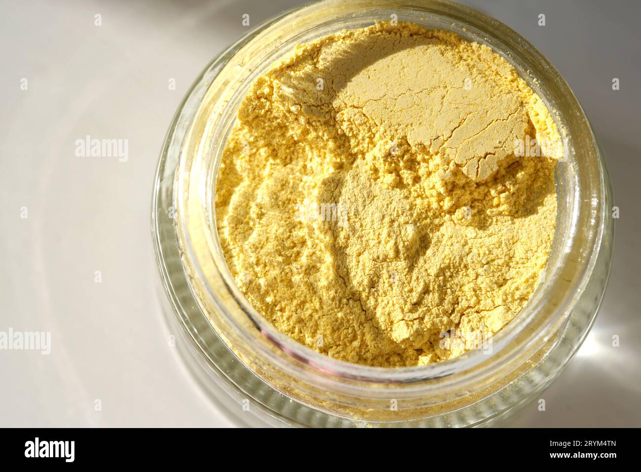 Un vaso aperto di uno scrub facciale curcuma giallo che ne mostra la consistenza. Foto Stock