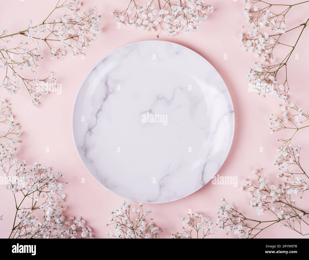 Romantico ambiente da tavolo in colori rosa. Sfondo rosa pastello chiaro con cornice di fiori bianchi Foto Stock
