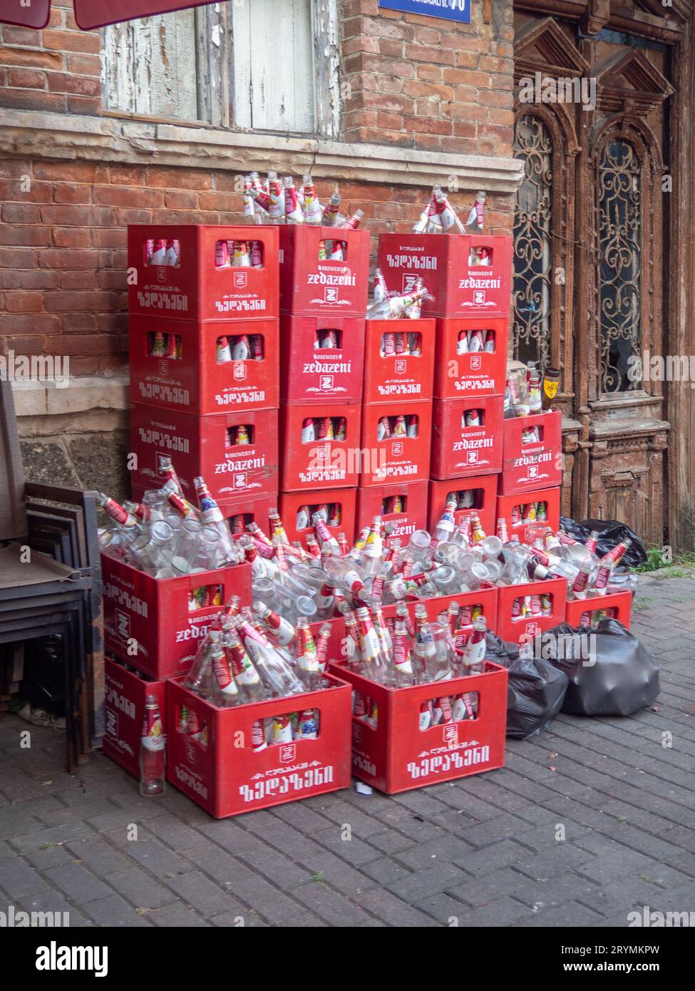 Batumi, Georgia. 09.30.2023 scatole nel cortile posteriore con contenitori di vetro. Molte bottiglie vuote in scatole. Imballaggio con limonata. Molte bottiglie vuote di Zid Foto Stock