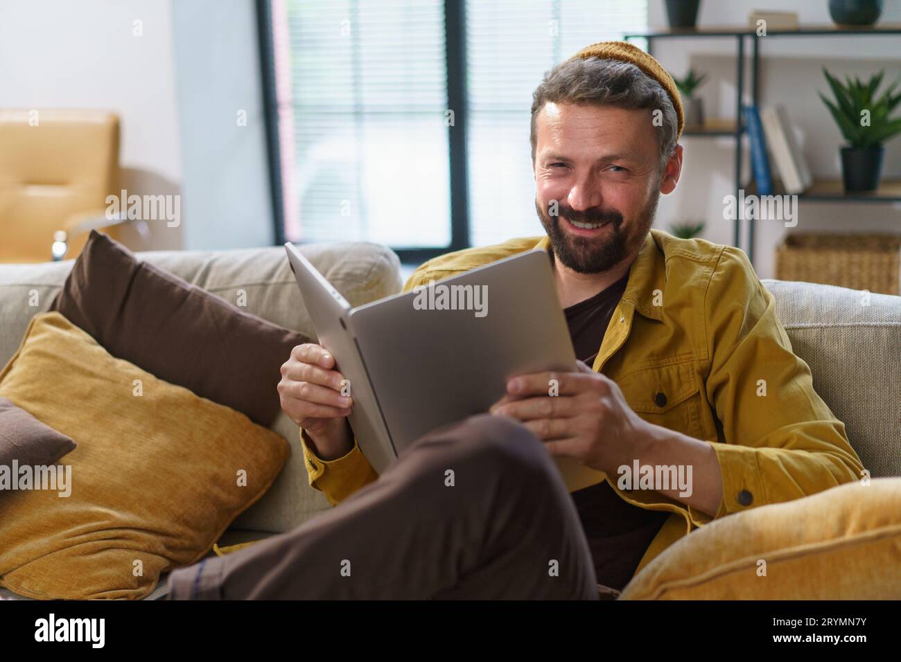 Gli studenti che si comportano in modo ingannevole si siedono sul divano e tengono il notebook come un libro in casa. Concetto di barare, mettere in evidenza lo studente" Foto Stock