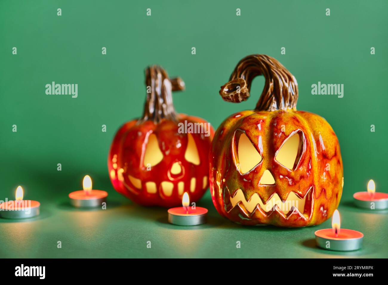 Composizione di Halloween con zucche in ceramica fai da te, lanterna jack e candele su sfondo verde pino Foto Stock