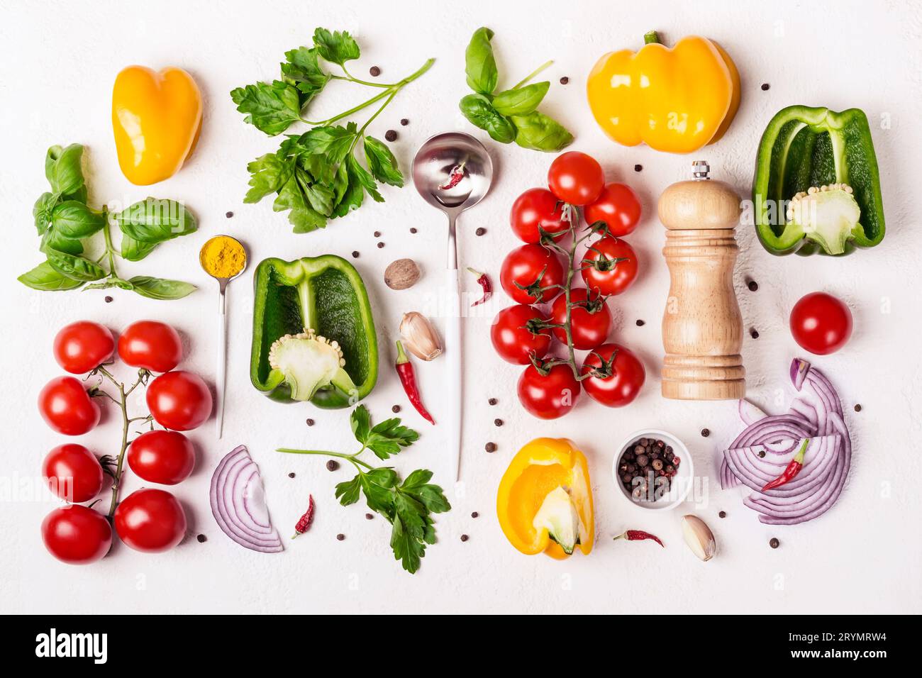 Varietà di verdure fresche, mulino per spezie e cucchiaio con olio d'oliva. Background gastronomico e concetto di cucina Foto Stock