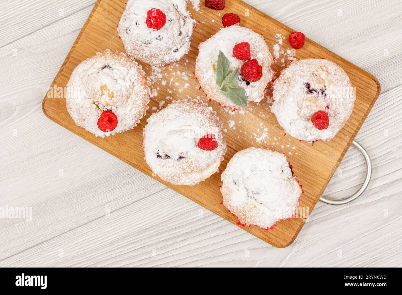 Muffin alla frutta fatti in casa cosparsi di zucchero a velo e lamponi freschi Foto Stock