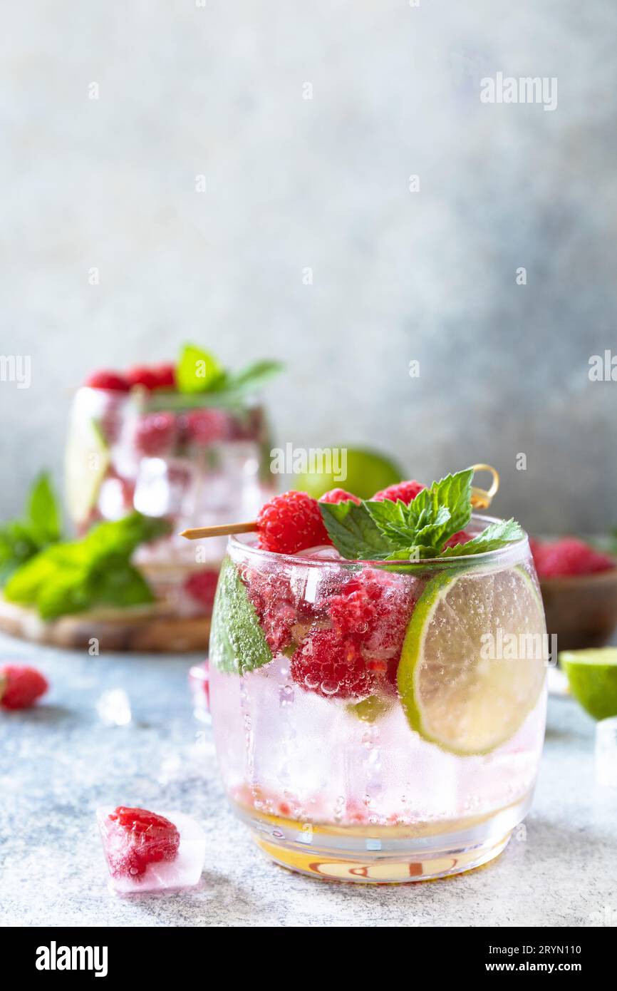 Cocktail sseltzer duro con lamponi e lime su un tavolo in pietra grigia. Spazio di copia. Foto Stock