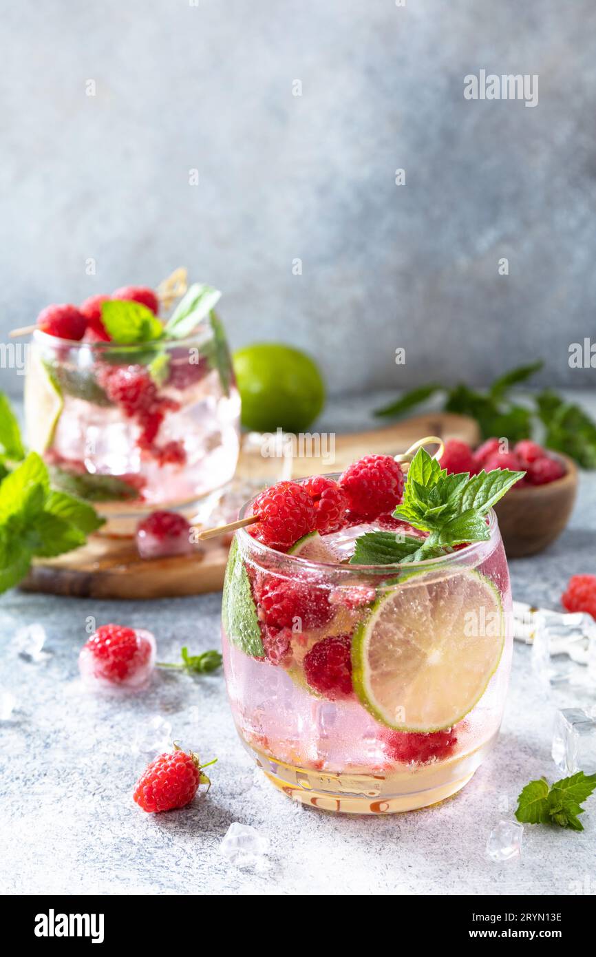 Cocktail sseltzer duro con lamponi e lime su un tavolo in pietra grigia. Spazio di copia. Foto Stock