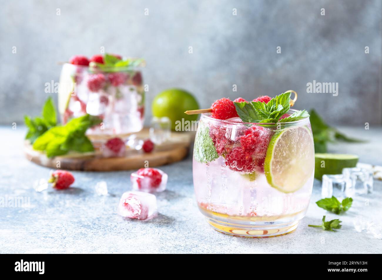 Cocktail sseltzer duro con lamponi e lime su un tavolo in pietra grigia. Spazio di copia. Foto Stock