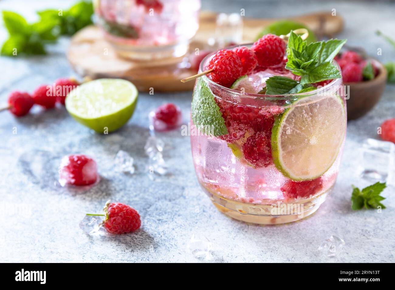 Cocktail seltzer duro con lamponi e lime su un tavolo in pietra grigia. Foto Stock