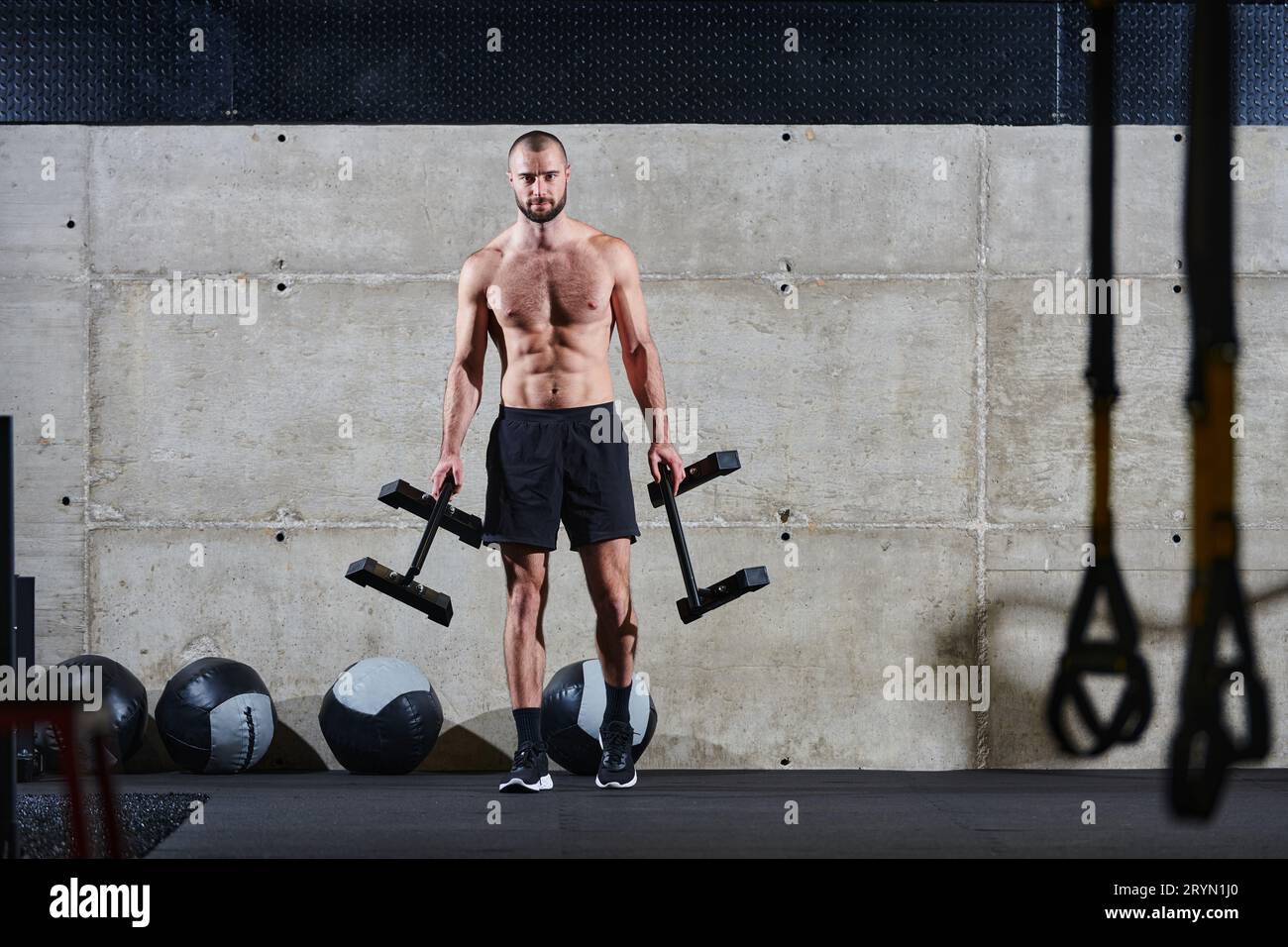 Un uomo muscoloso esegue esercizi alle spalle in una palestra moderna, mostrando la sua forza e dedizione al fitness. Foto Stock